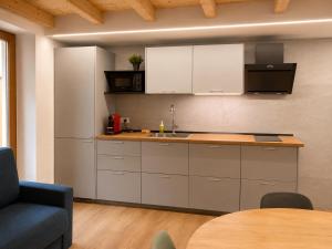 a kitchen with white cabinets and a sink and a table at Clelia appartamento 6 posti vicino le piste da sci in Temù +6 photos