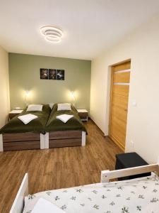 a bedroom with two beds and a wooden floor at Zója Apartmanház in Nagykanizsa