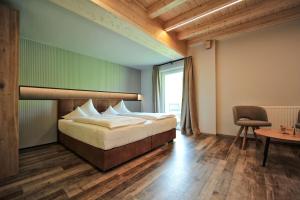 a bedroom with a bed and a table and a chair at Pension Garni Hochmoos in Lermoos