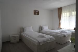 two beds in a white room with a window at Къща за гости Мекана in Borino