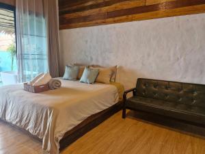 a bedroom with a bed with a couch and a window at Doichang Riverhouseดอยช้างริเว่อเฮาส์ in Ban Huai Khai