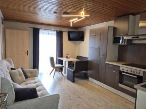 a living room with a couch and a kitchen with a table at Ferienwohnung Weindl Lucia in Kollnburg +10 photos