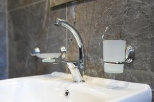 a bathroom sink with a faucet and a toilet paper holder at Къща за гости Мекана in Borino +18 photos