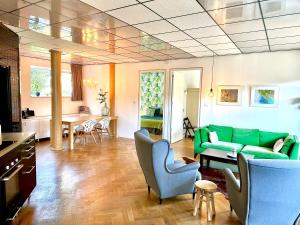 a living room with a green couch and chairs at De Oude Kleuterschool in Zoelen