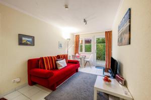 a living room with a red couch and a table at Bungalow Westerland Kampstrasse in Westerland