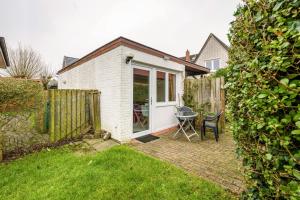 a small white house with a table in the yard at Bungalow Westerland Kampstrasse in Westerland
