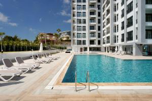 a swimming pool with lounge chairs and a building at Annabella Residence in Alanya