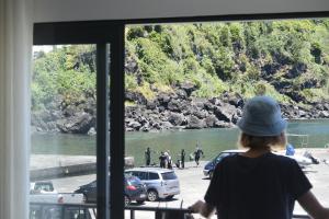 a woman looking out of a window at a river at Casa do Porto - Santa Cruz B&B in Ribeiras