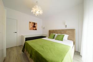 a bedroom with a bed with green sheets and a chandelier at Smile Apartments in Bucharest