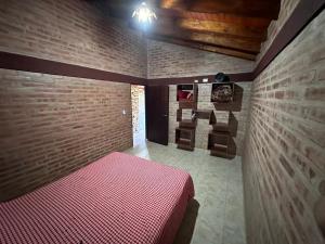 a bedroom with a pink bed in a brick wall at Al pie de la Sierra in Pueblito +8 photos