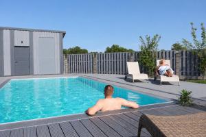 a man laying on a deck next to a swimming pool at Atpūtas komplekss "Seaside Apartments Roja" in Roja