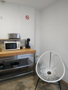 a white chair in a kitchen with a microwave at Alojamiento Gofioplaya in Arinaga