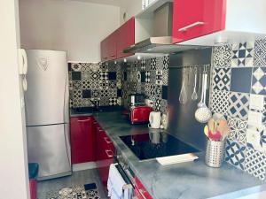 a kitchen with red cabinets and a stainless steel refrigerator at Casamea - Vue Mer, Clim & Parking, Proche Plage in Ajaccio +5 photos