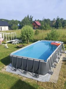 a large swimming pool in a yard with a table at Osada Szwedzka Domek Plus in Rusinowo
