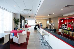 a restaurant with a bar with white chairs and tables at Holiday Inn Express Rotherham - North by IHG in Rotherham