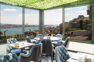 ein Restaurant mit Tischen und Stühlen und großen Fenstern in der Unterkunft Marble Hotel in Istanbul