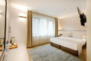 ein Schlafzimmer mit einem weißen Bett und einem großen Fenster in der Unterkunft Marble Hotel in Istanbul