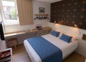 a bedroom with a bed and a desk and a window at Brit Hotel Montpellier Euromédecine in Montpellier