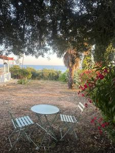 a table and two chairs with the ocean in the background at Villa Naturaleza in Loutsa