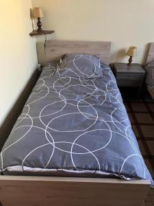 a bed with a blue and white comforter and two lamps at Tastet in MouscardÃ¨s