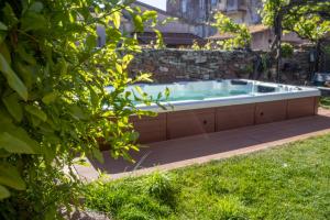 a hot tub in a yard with a stone wall at S'Asilo Boutique B&B - North Sardinia - Village stay in Banari
