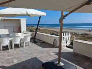 a patio with chairs and an umbrella and the beach at the suite on the beach in Torvaianica