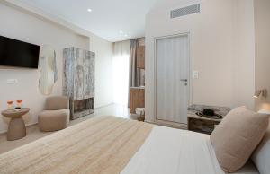a white bedroom with a bed and a chair at Petra Studios in Palaiochora