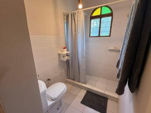 a bathroom with a toilet and a shower and a window at Bahari Paje Beach House in Paje +29 photos