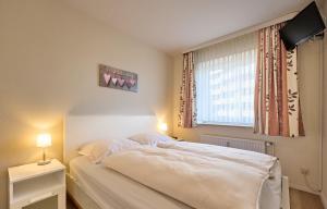 a bedroom with a white bed and a window at Düne, App 9 in Duhnen