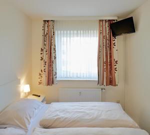 a bedroom with a white bed and a window at Düne, App 9 in Duhnen +8 photos