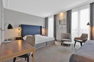 a hotel room with a bed and a desk and chairs at Hôtel Londres et New York - Teritoria in Paris