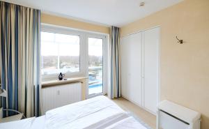 a bedroom with a bed and a window at Haus Schildt, FeWo 6 in Duhnen
