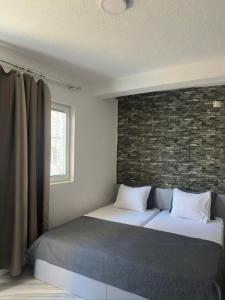 a bedroom with a bed and a brick wall at OneRoom in Ohrid