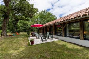 ein Haus mit einer Terrasse mit Tisch und Stühlen in der Unterkunft Gîte du caché in Labrit