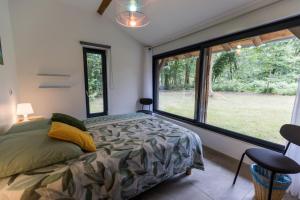 ein Schlafzimmer mit einem Bett und einem großen Fenster in der Unterkunft Gîte du caché in Labrit + 40 Fotos