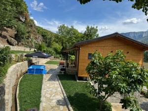 a log cabin with a garden and an umbrella at Guesthouse Deshnica in Këlcyrë