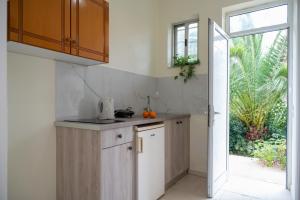 a kitchen with white cabinets and an open door at Kalofonos Studios in Laganas +15 photos