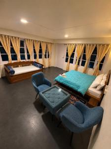 a bedroom with a bed and a couch and chairs at Lungta Homes in Bomdila