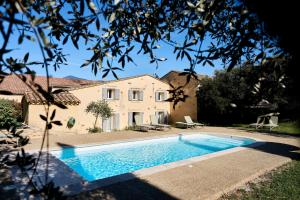 a swimming pool in front of a house at Clos Saint-Michel Resort & Spa in Malaucène