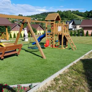 a playground with a wooden swing set on grass at Domki Lawendowa Skarpa in Zawóz