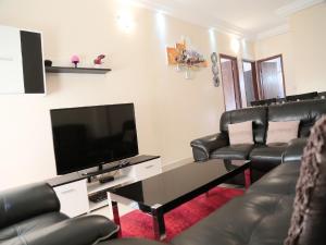 een woonkamer met lederen stoelen en een flatscreen-tv bij Apartment 25B11 Mixta in Dakar