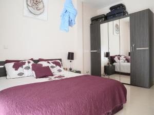 Apartment 25B11 Mixta في داكار: غرفة نوم مع سرير أرجواني وخزانة