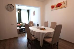 a dining room with a table with chairs and a clock at Apartment Jugo in Preko