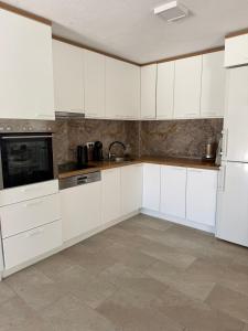 a white kitchen with white cabinets and appliances at Villa Tri tačke in Debeljaci