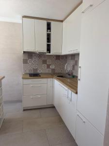 a kitchen with white cabinets and a sink at Villa Tri tačke in Debeljaci +6 photos