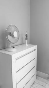 a white dresser with a fan on top of it at Apartament Harmony in Ełk +21 photos