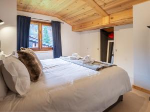 a bedroom with a large white bed with a wooden ceiling at Chalet Bolay in Montriond +22 photos