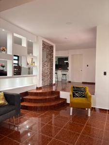 a living room with stairs and a yellow chair at Casa ejecutiva para 10 personas in Gómez
