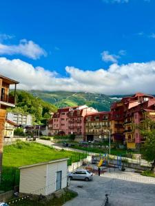 a group of buildings and a parking lot with cars at Apart Hotel TRIBU Bakuriani in Bakuriani