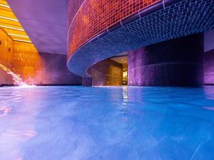 ein Schwimmbad in einem Gebäude mit blauem Wasser in der Unterkunft Sofitel Munich Bayerpost in München
